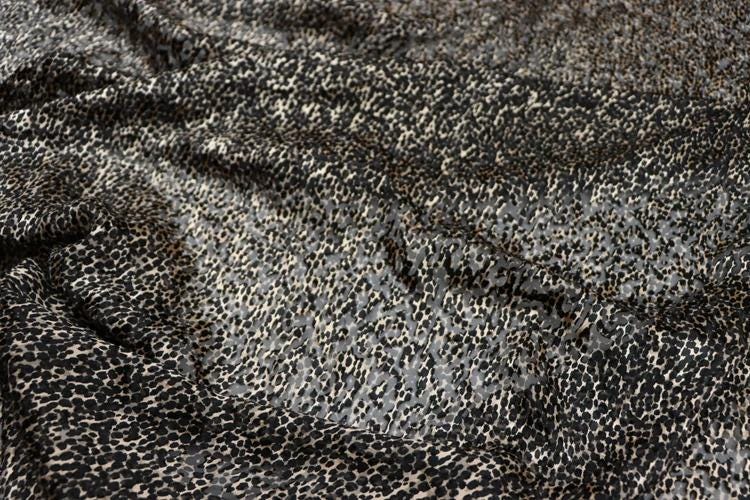 a close-up view of a fabric with a black and white spotted pattern, resembling a leopard print design.