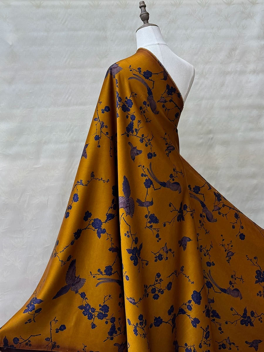 A mannequin wearing a vibrant yellow and blue floral print dress with a flowing, draped silhouette.