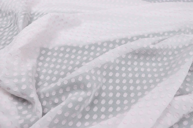 a close-up view of a fabric with a white and gray polka dot pattern. The fabric appears to be crumpled and wrinkled, giving it a soft and casual appearance.