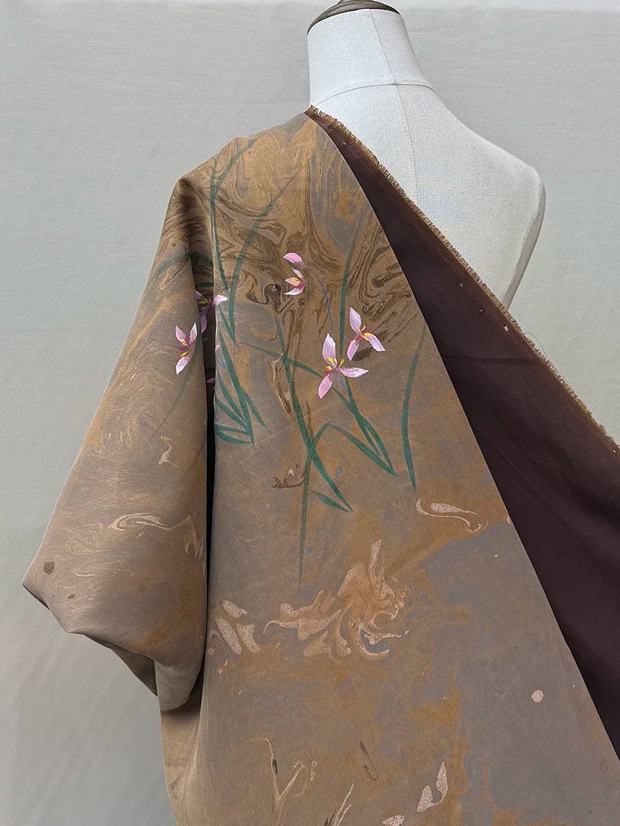 A mannequin wearing a brown and gold floral print blouse with a dark brown shawl draped over it.