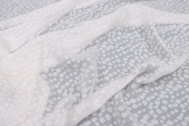 a close-up view of a white fabric with a pattern of small white dots or circles on it.