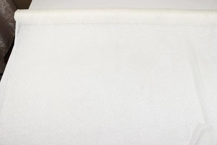 a white fabric with a dotted pattern, possibly a piece of lace or a similar type of material.