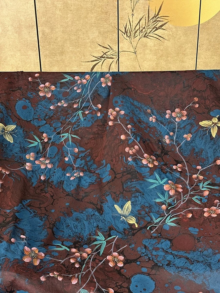 a vibrant floral pattern with a mix of blue, red, and yellow colors, including flowers, leaves, and branches. The pattern appears to be a textile or fabric design, with the flowers and leaves arranged in a visually appealing manner.