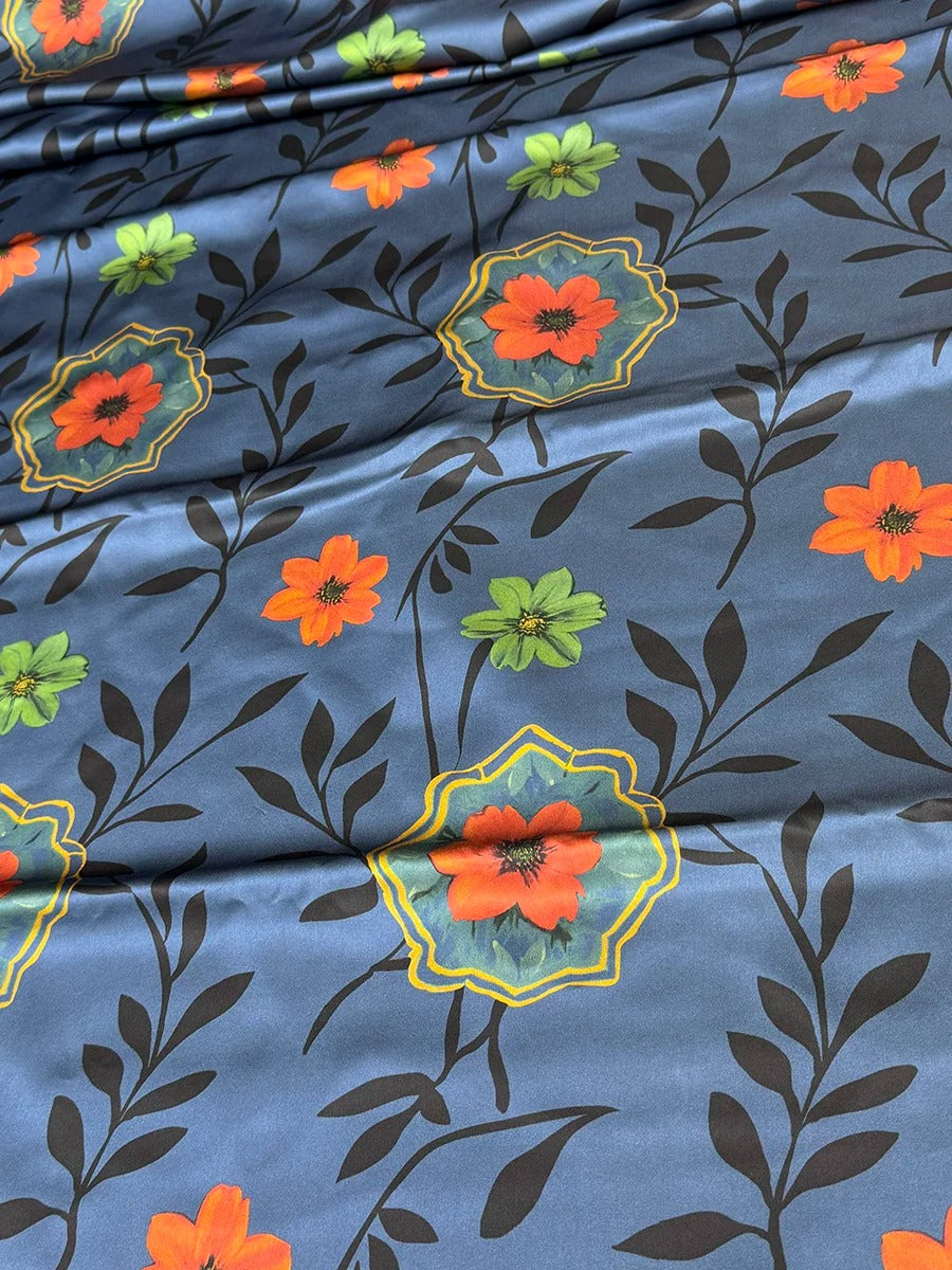 a close-up view of a fabric with a floral pattern. The fabric has a blue background with orange and green flowers and leaves, creating a vibrant and colorful design.