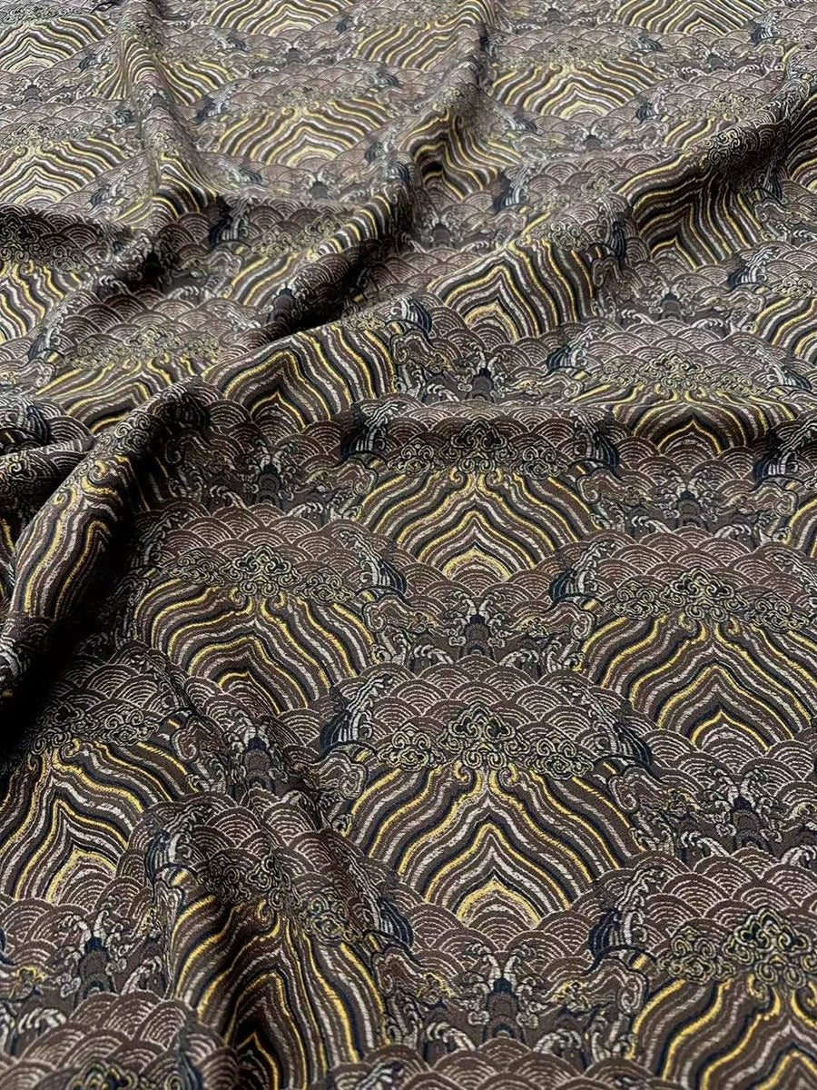 a close-up view of a fabric with a repeating pattern of brown and yellow stripes, resembling a wave or a floral design. The fabric appears to be made of a soft, textured material, and the pattern is intricate and detailed.