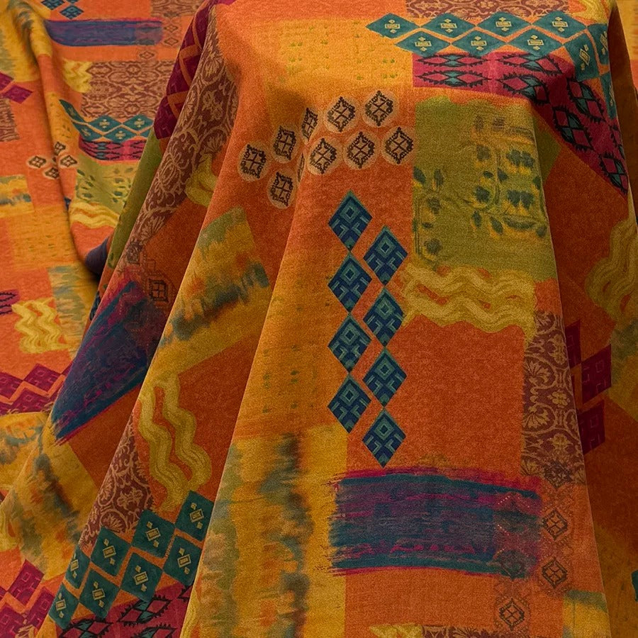 a vibrant, multicolored fabric with a variety of geometric patterns and designs, including diamond shapes, stripes, and floral motifs. The fabric appears to be a textile or fabric with a bold, eye-catching pattern.