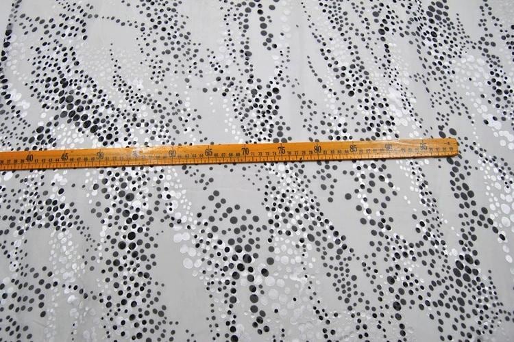 a close-up view of a ruler placed on a surface with a pattern of black and white dots.