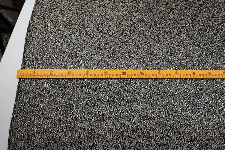 a close-up view of a yellow ruler placed on a textured fabric surface, likely measuring the length or width of the fabric.