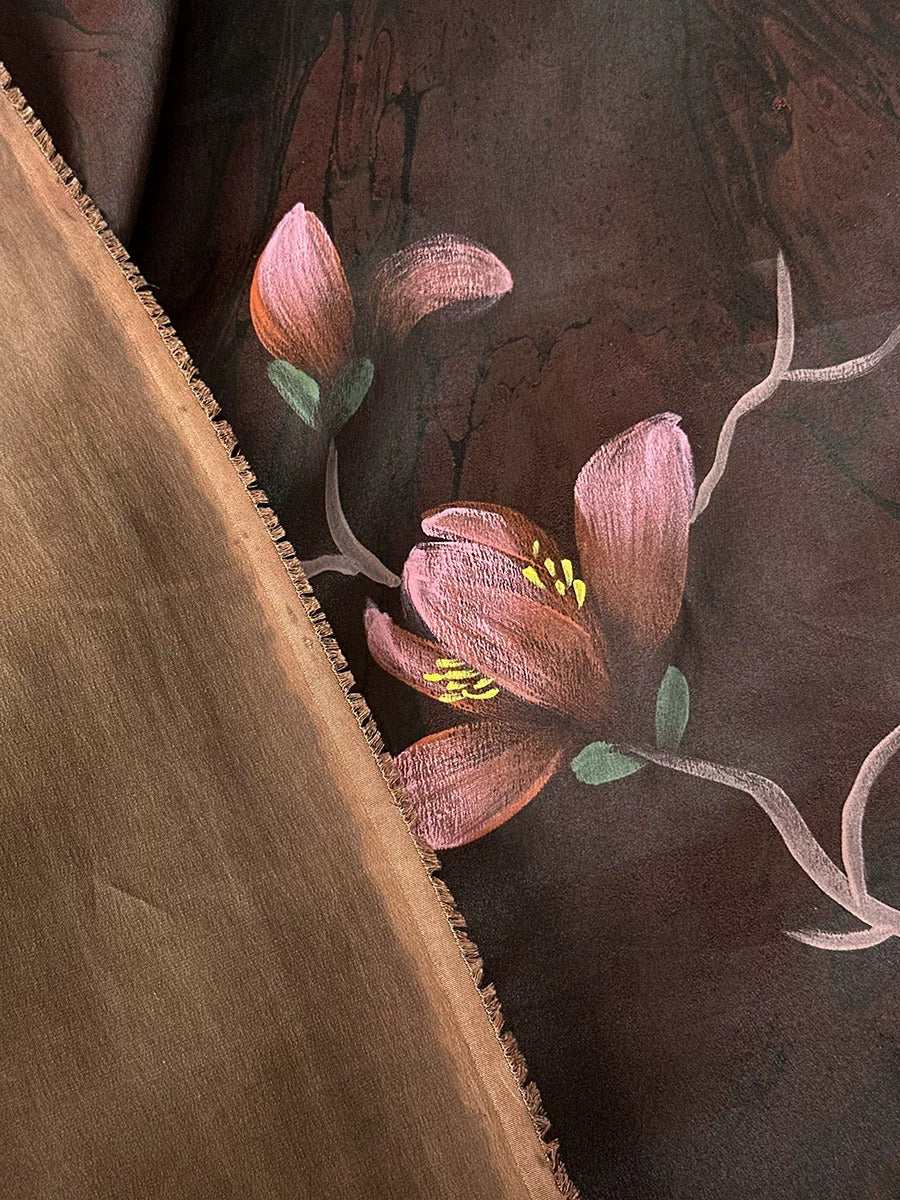 a close-up view of a brown fabric with a floral design on it. The design includes pink flowers with yellow centers, and the fabric appears to be made of a soft, plush material.
