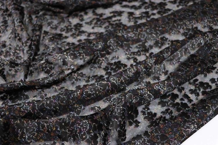 a close-up view of a fabric with a floral pattern, featuring a mix of black and gray colors.