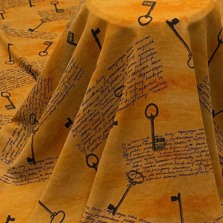 a close-up view of a fabric with a repeating pattern of black keys and text. The keys are arranged in a diagonal pattern, creating a visually striking and textured effect. The text appears to be handwritten and is scattered throughout the fabric, adding an artistic and unique touch to the overall design.