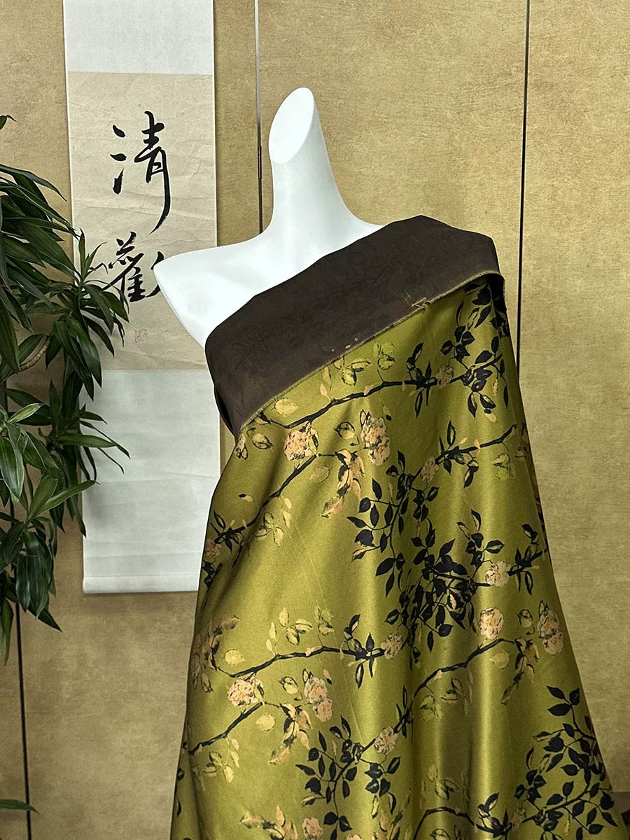 A mannequin wearing a green and black floral print dress with a brown top, displayed against a beige wall with a Chinese character hanging on it.