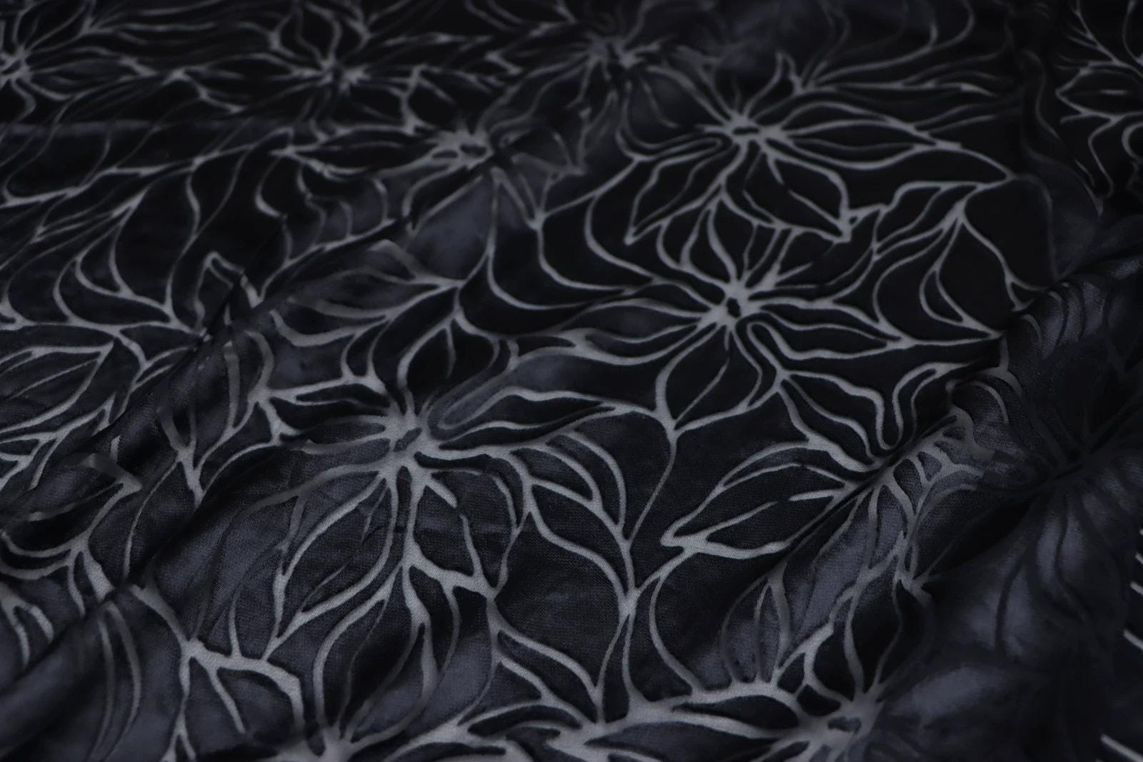 a close-up view of a fabric with a repeating floral pattern in shades of black and gray.
