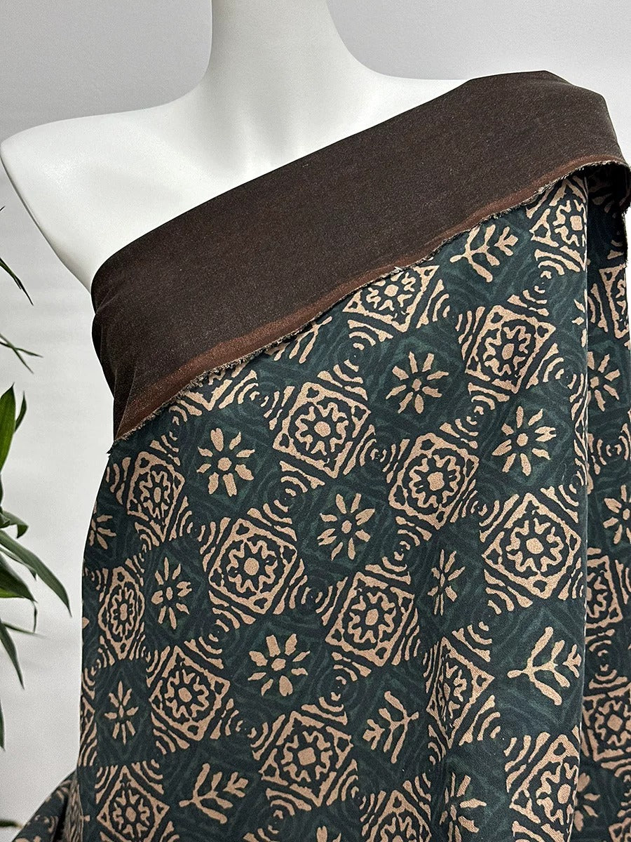 A mannequin wearing a brown and green patterned fabric draped over its shoulder.