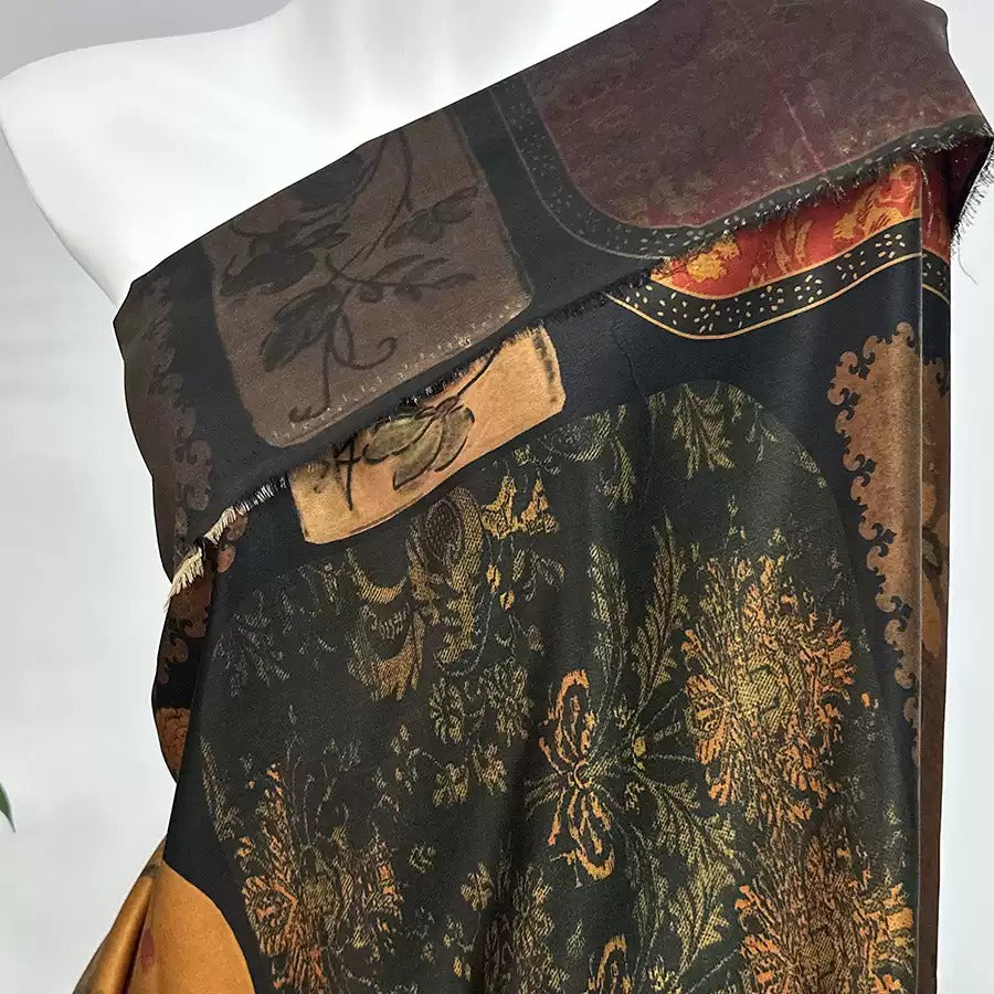 a mannequin wearing a colorful, patterned fabric with a mix of black, gold, and red colors.