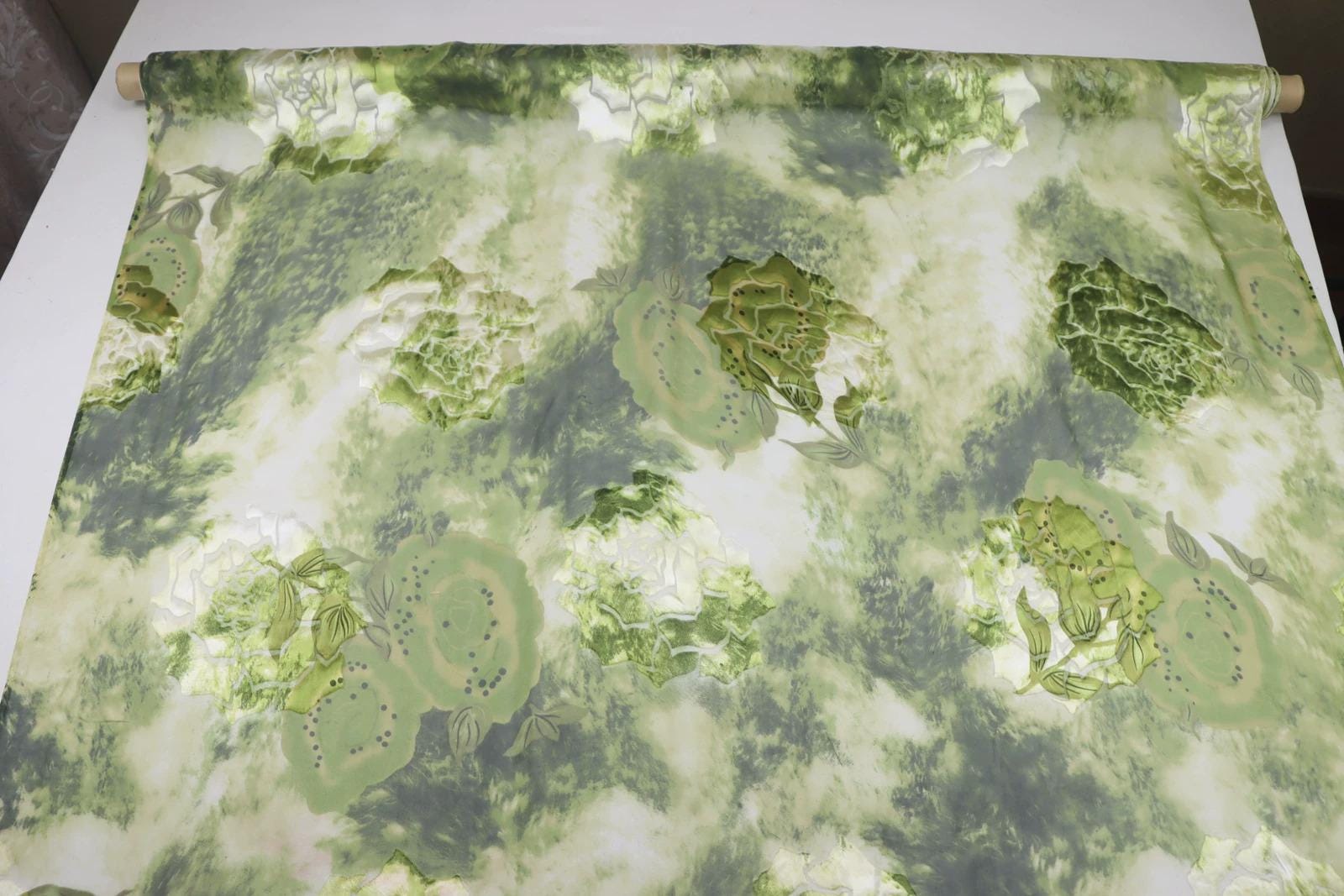 a fabric with a green and white floral pattern, including various types of flowers and leaves.