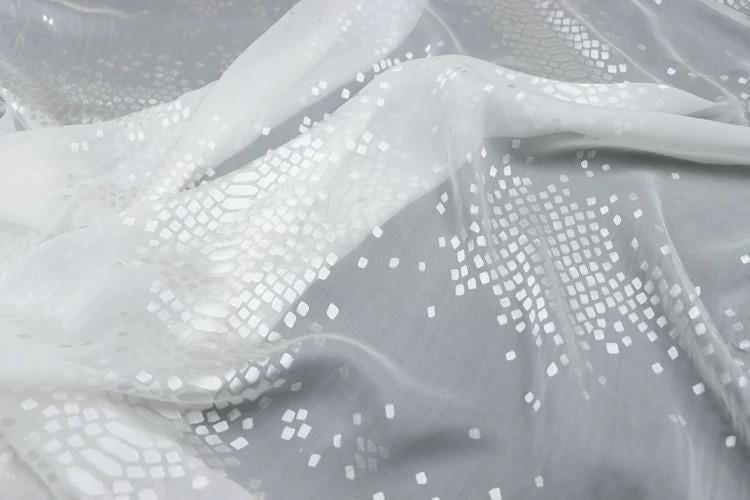 a close-up view of a white fabric with a pattern of small white squares or dots on it.