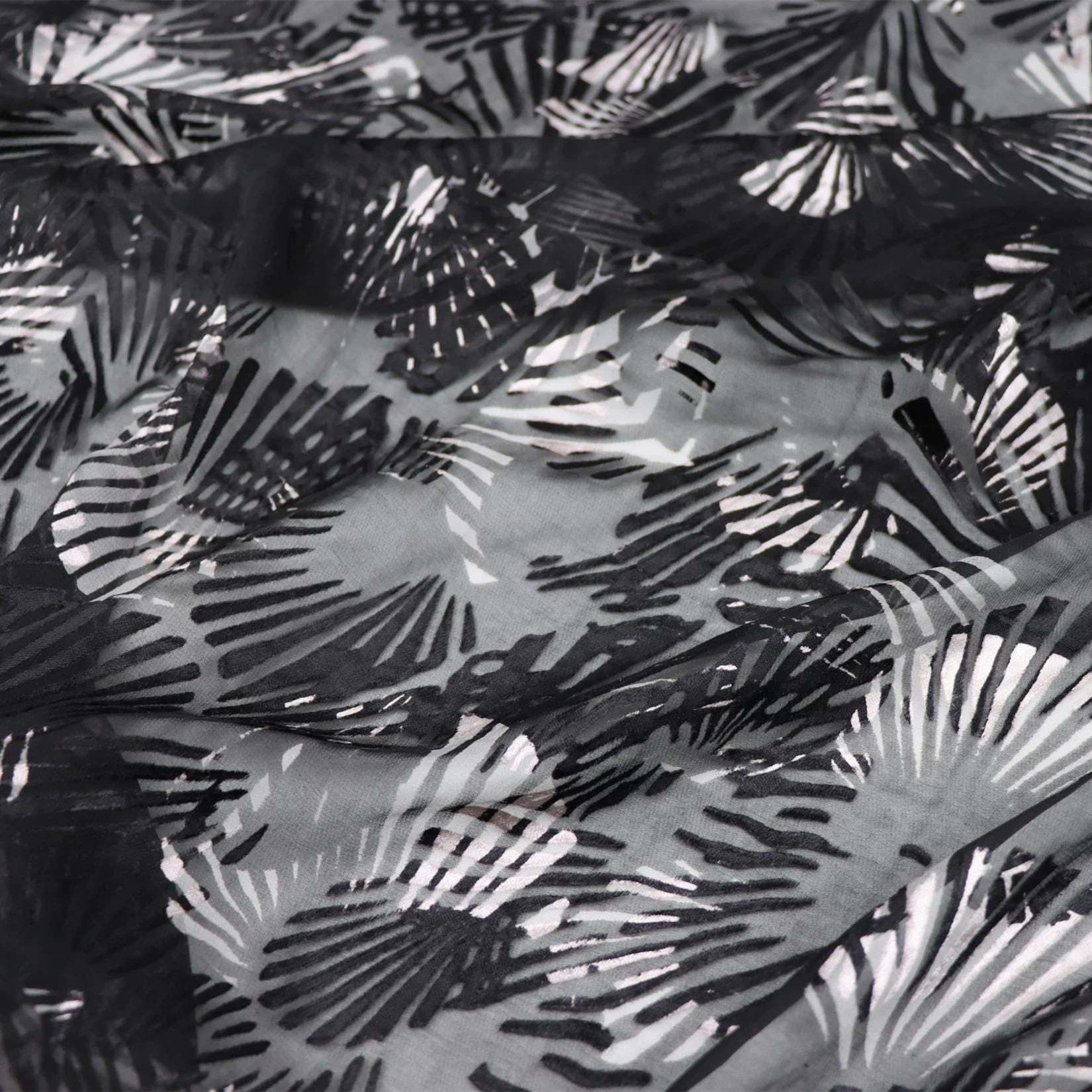 a close-up view of a fabric with a black and white pattern of overlapping shells or leaves.