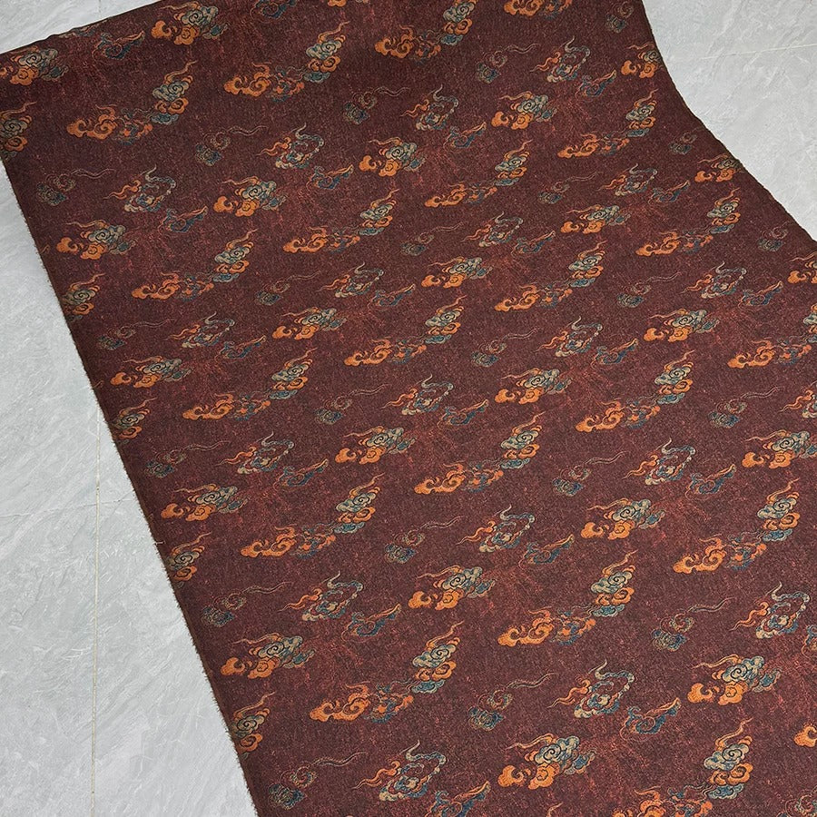 a dark red fabric with a repeating pattern of orange and blue clouds or shapes.