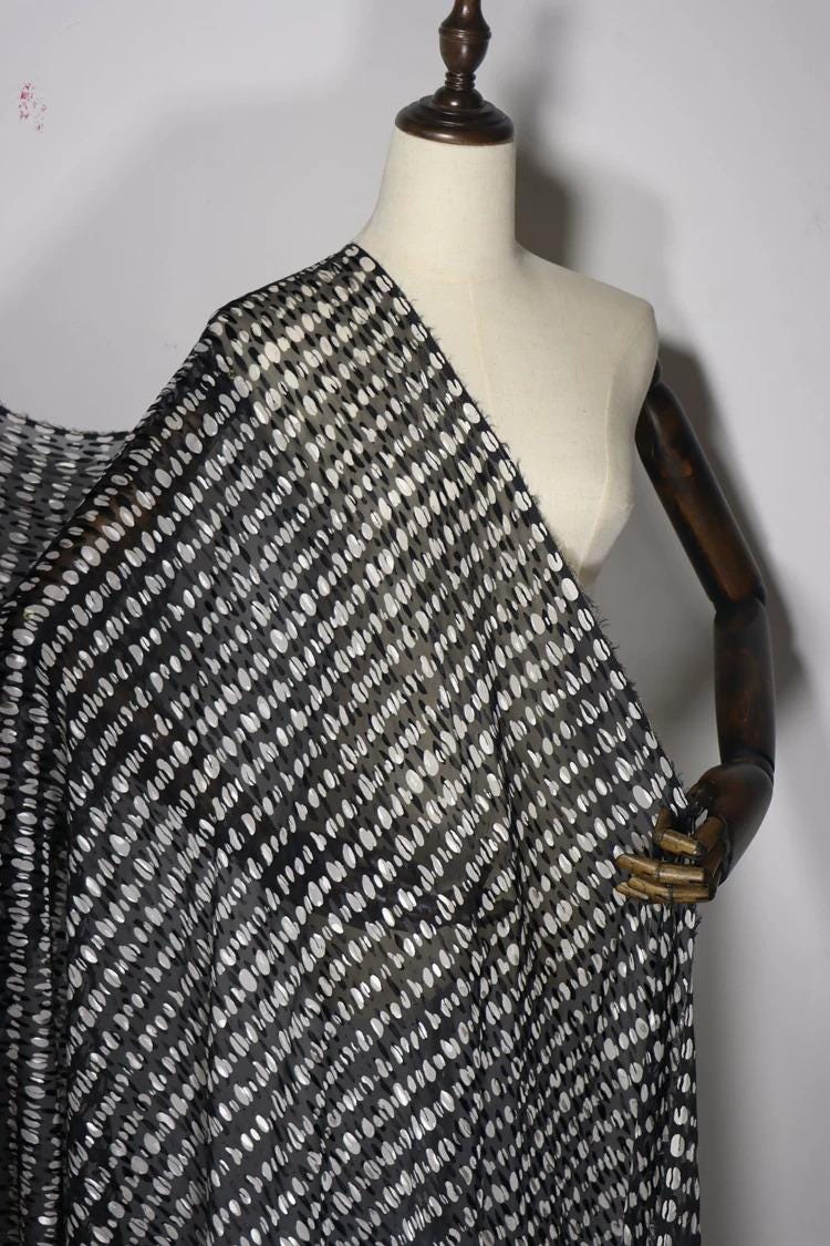 A mannequin wearing a black and white patterned fabric draped over it.