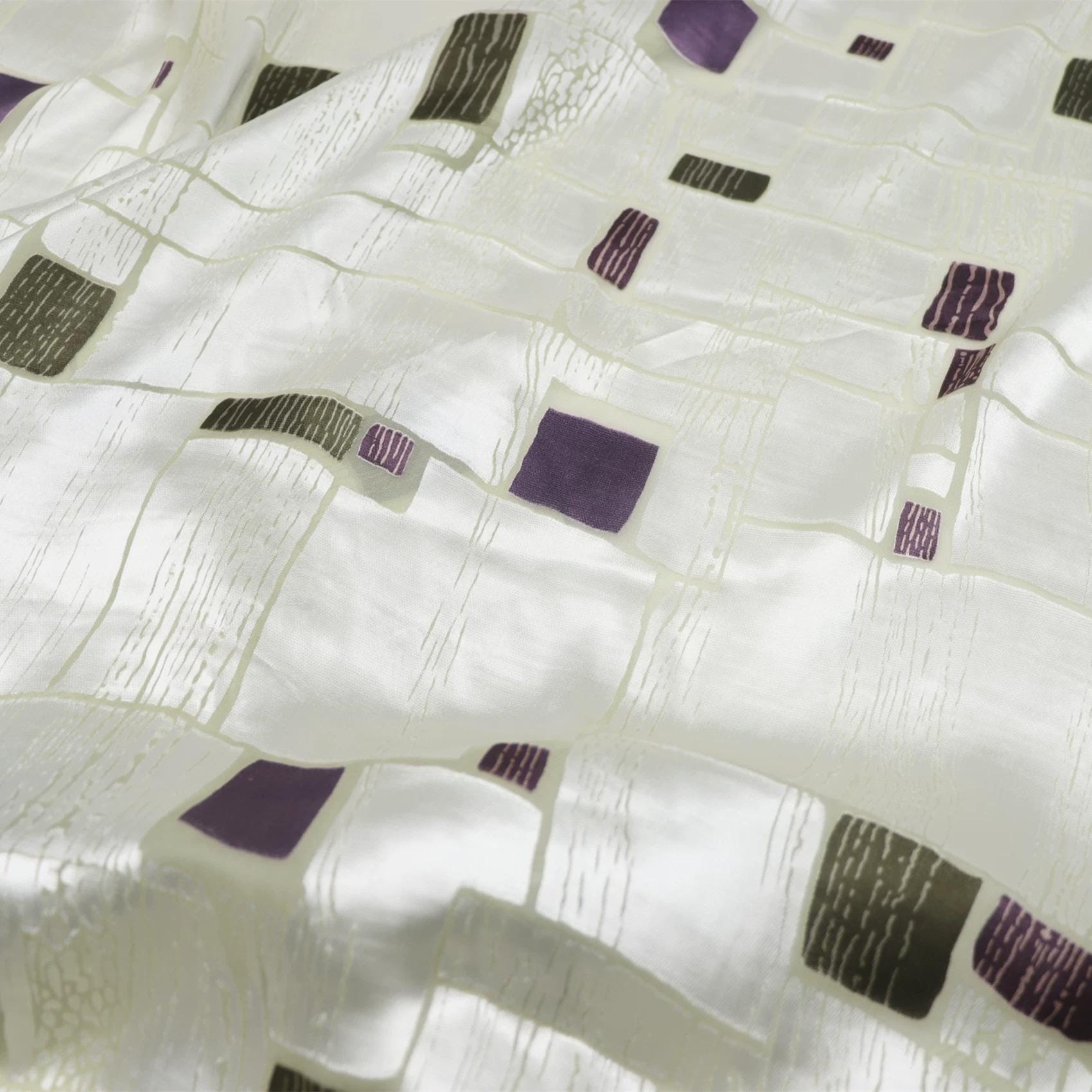 a close-up view of a fabric with a geometric pattern of squares and rectangles in various shades of purple and green.