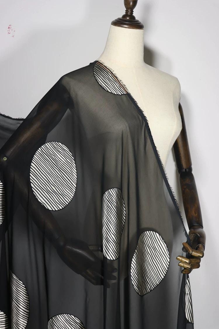 A mannequin wearing a black and white patterned fabric draped over its body.