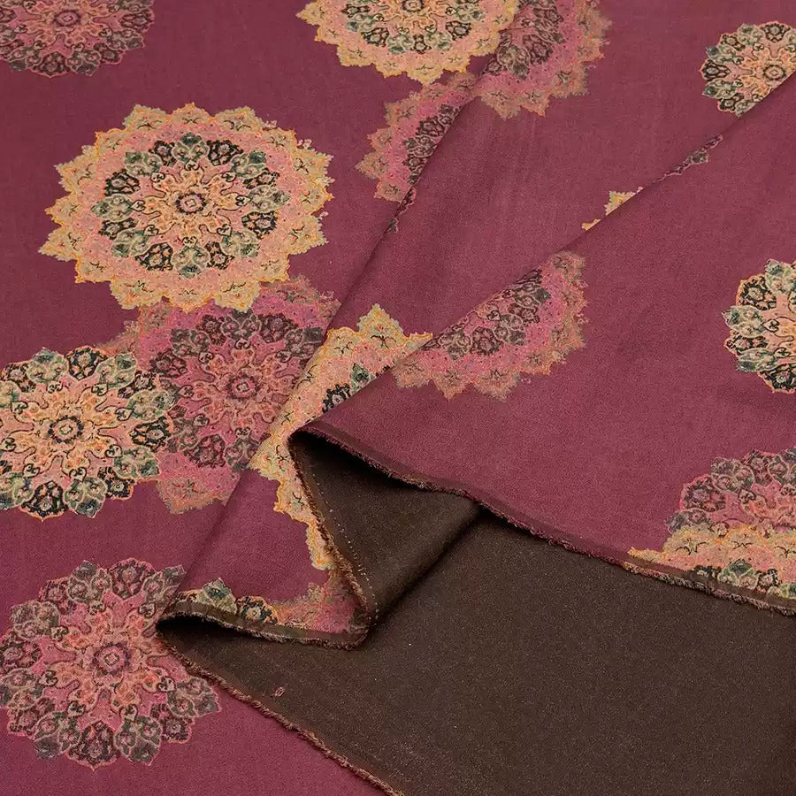 a close-up view of a fabric with a floral pattern in shades of pink and brown. The fabric appears to be a piece of cloth or textile, with a rich, burgundy-colored background. The pattern consists of multiple floral designs, creating a visually striking and intricate design.