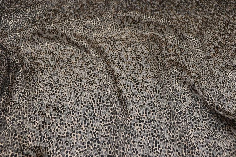 a close-up view of a fabric with a distinctive leopard print pattern. The fabric appears to be a blend of black and white colors, with the pattern resembling the spots of a leopard. The fabric is crumpled, giving it a textured appearance.