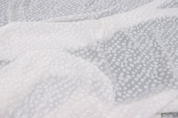 a close-up view of a white fabric with a polka dot pattern.