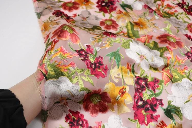 a close-up view of a fabric with a vibrant floral pattern, featuring a variety of colorful flowers such as red, white, yellow, and green.