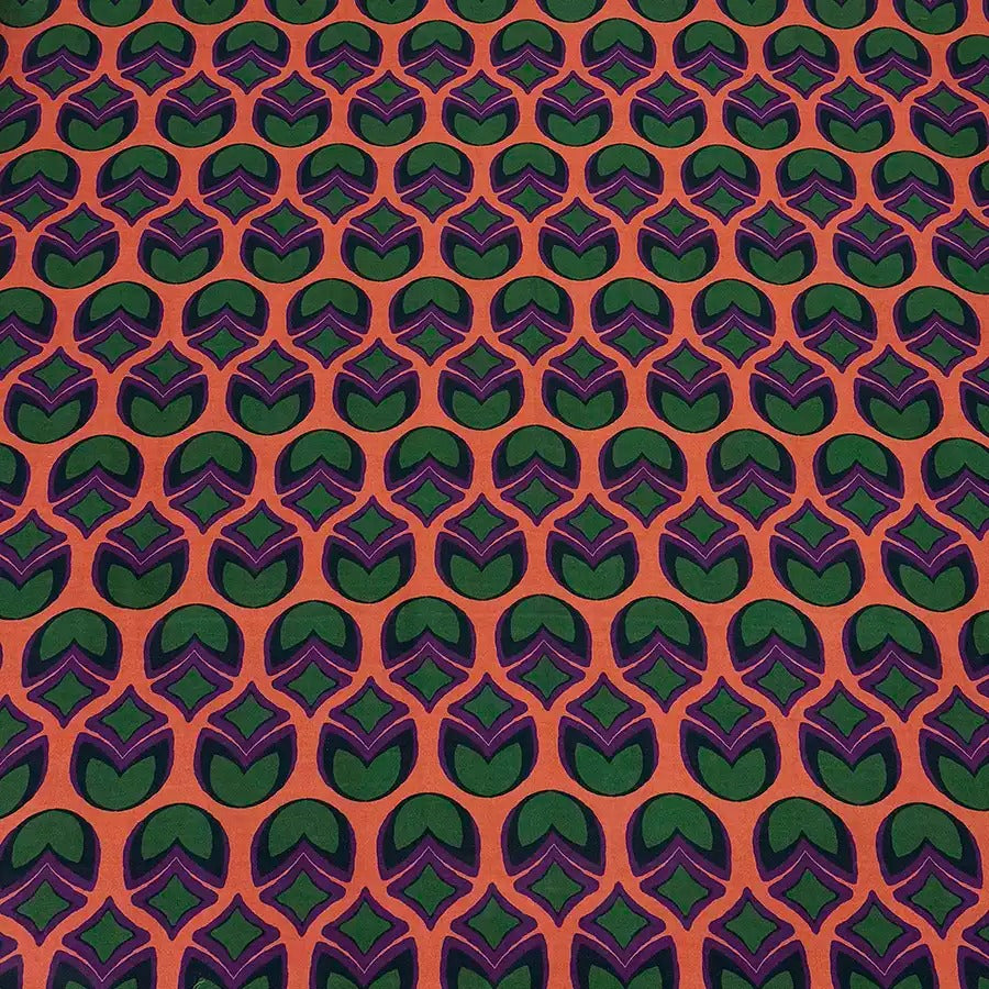 a repeating pattern of green and orange circles on a fabric surface.