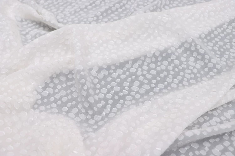 a close-up view of a white fabric with a pattern of small white dots or circles on it.