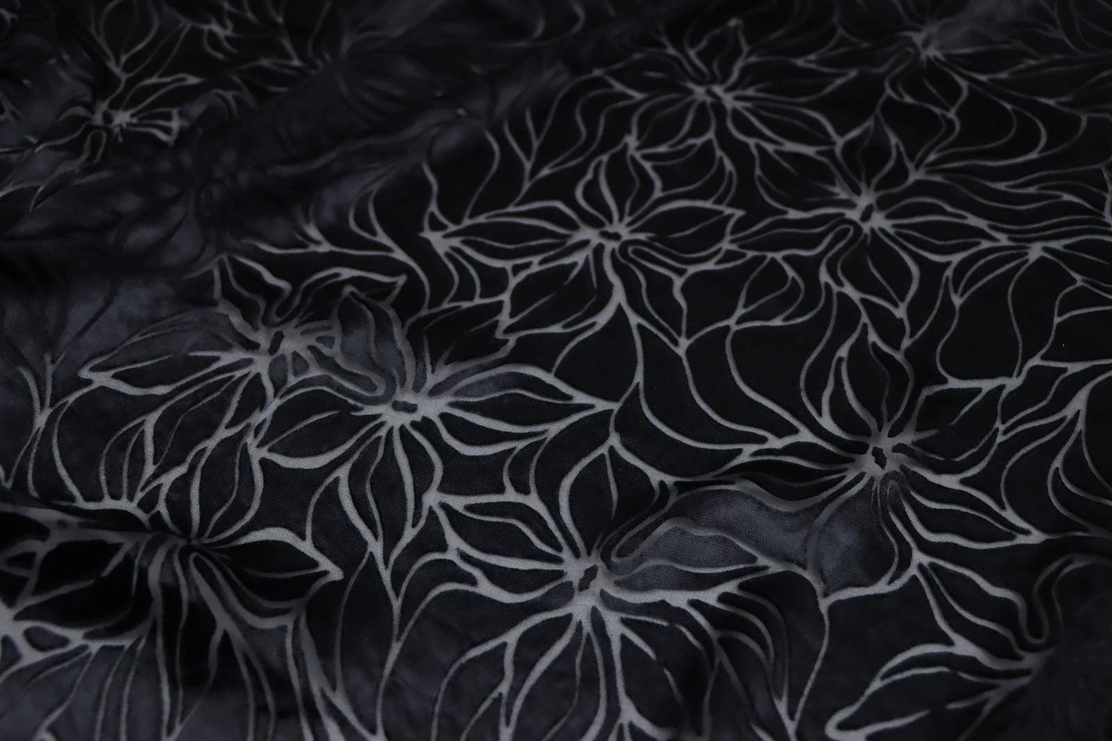 a close-up view of a fabric with a repeating floral pattern in black and white.