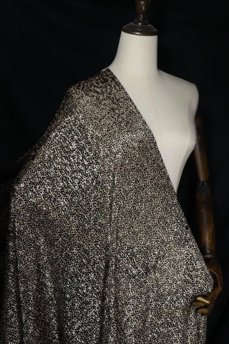A mannequin wearing a black and white patterned fabric draped over its body.