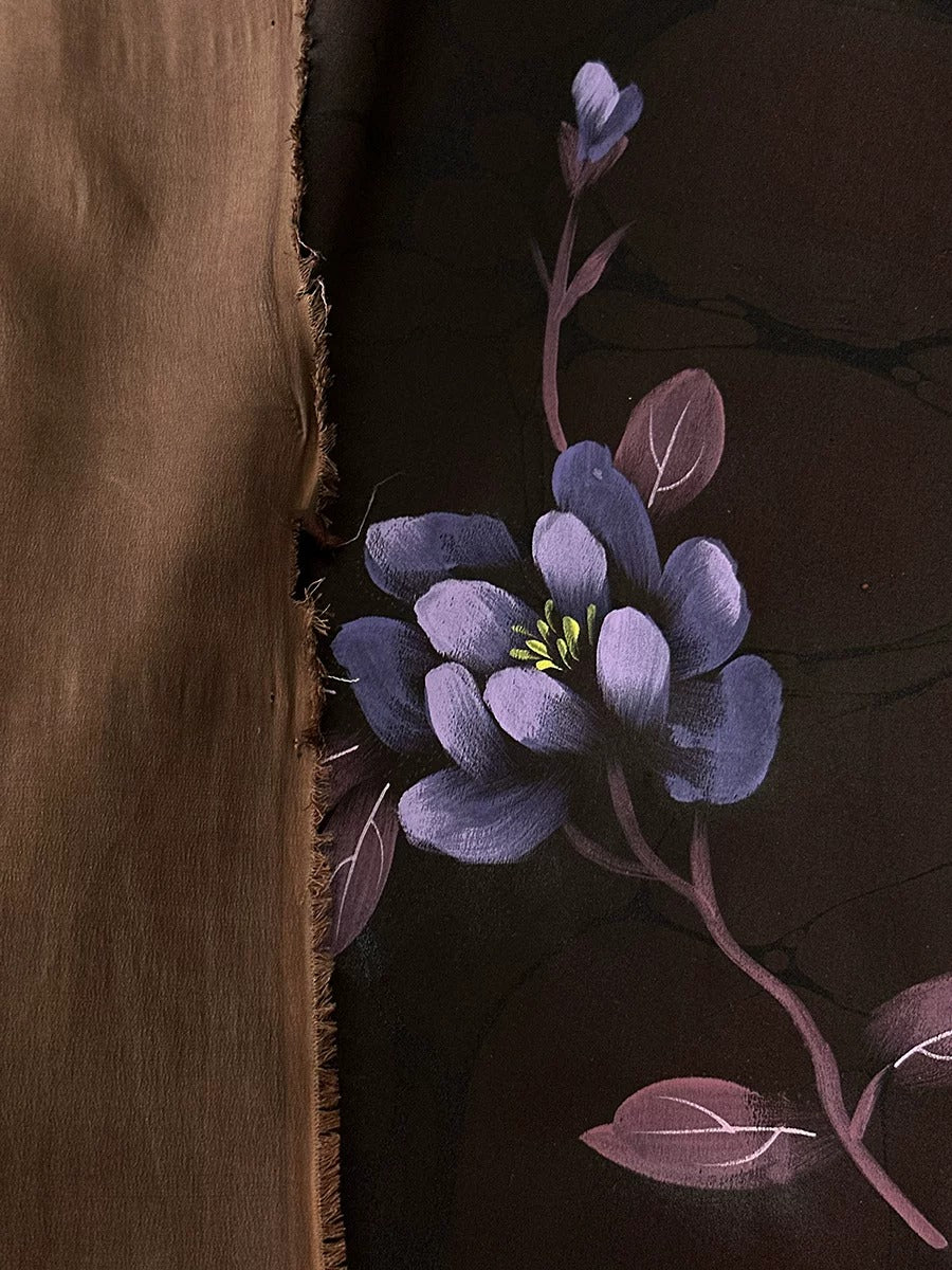 a close-up view of a purple flower with green leaves against a dark background.