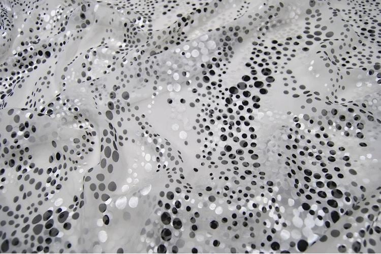 a close-up view of a fabric with a pattern of small black dots on a white background.