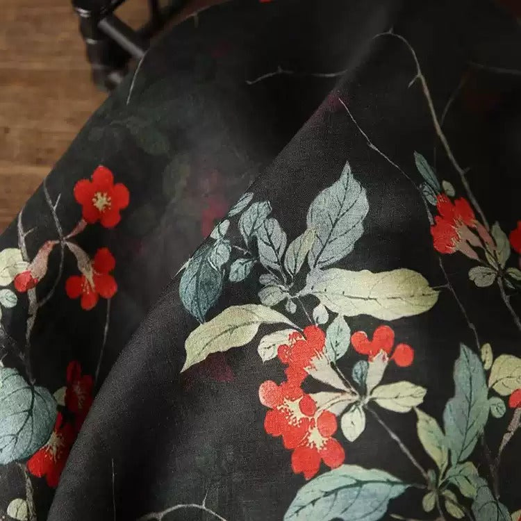 a close-up view of a fabric with a floral pattern, featuring red flowers and green leaves.