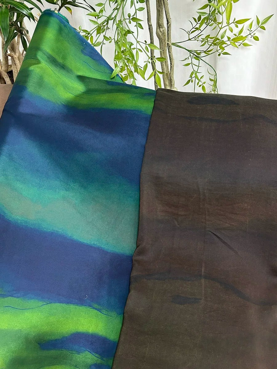 a close-up view of a fabric with a striking pattern of blue and green hues, contrasted against a dark brown fabric. The fabric with the blue and green pattern appears to be a piece of cloth, while the dark brown fabric is a separate piece of cloth. The background of the image is a simple white wall, with some greenery visible in the top left corner.