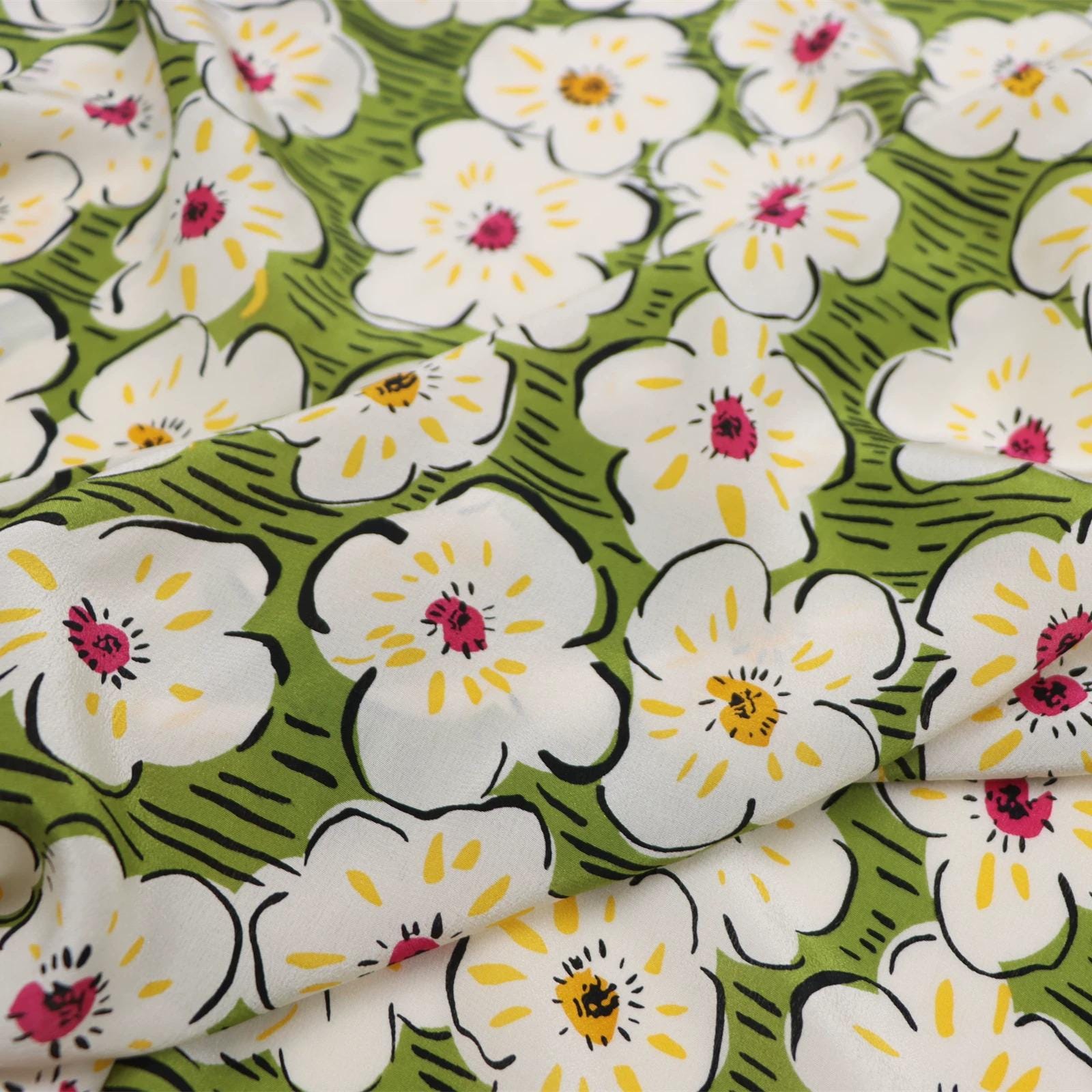 a close-up view of a fabric with a repeating pattern of white flowers with yellow centers against a green background.