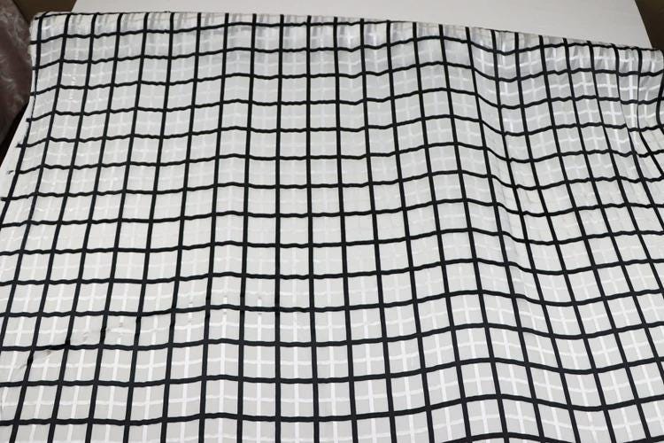a close-up view of a fabric with a grid-like pattern of black and white squares.