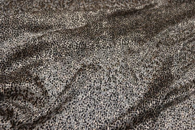 a close-up view of a fabric with a distinctive leopard print pattern. The fabric appears to be made of a material with a textured surface, resembling the appearance of a leopard's fur. The pattern consists of small, irregularly shaped dots or spots, creating a visually striking and textured effect.