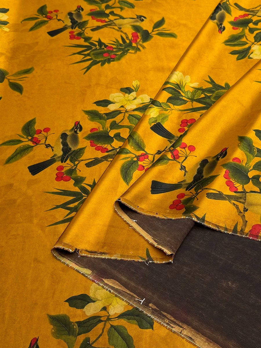 a close-up view of a fabric with a vibrant yellow and green floral pattern, including birds and berries. The fabric appears to be made of a shiny material, possibly silk or satin, and has a textured surface.