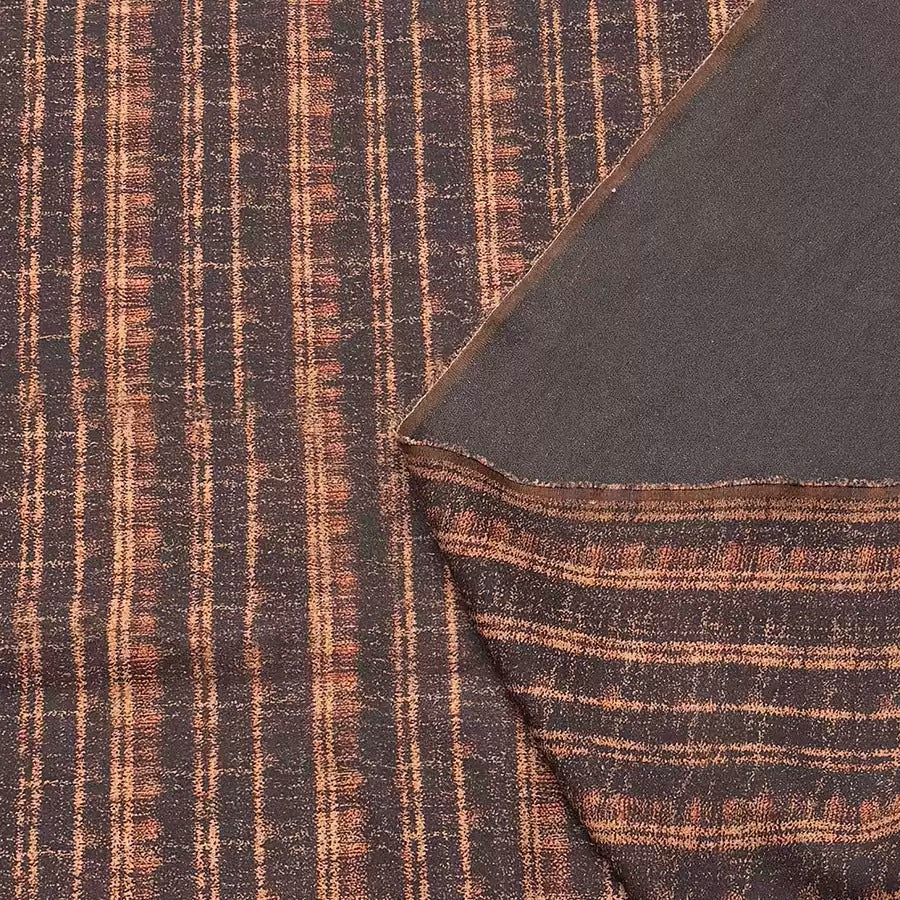 a close-up view of a fabric with a striped pattern in shades of brown and orange. The fabric appears to be made of a woven material, with a dark background and a lighter background. The fabric is folded over itself, revealing the intricate design and texture of the material.