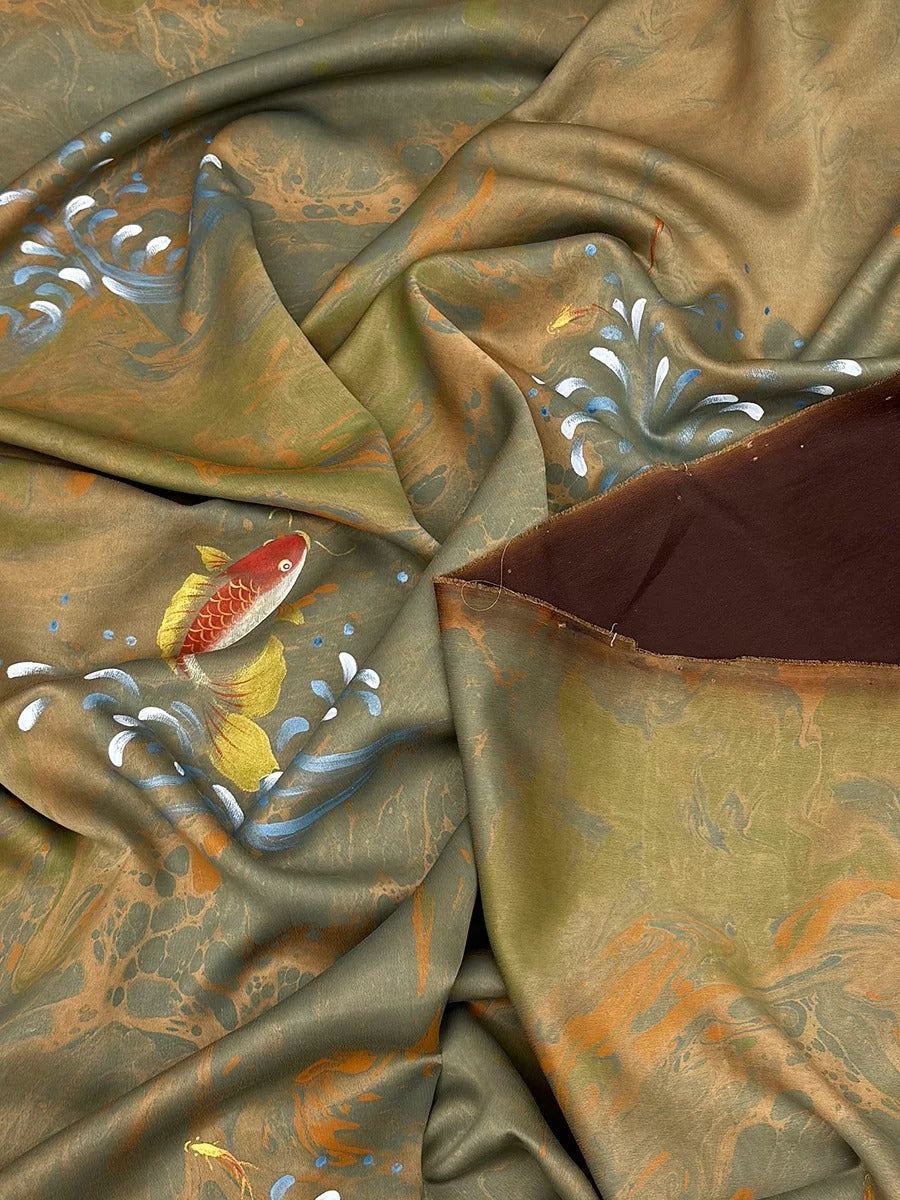 The image is a close-up view of a fabric with a fish design, featuring a mix of green, brown, and orange colors.