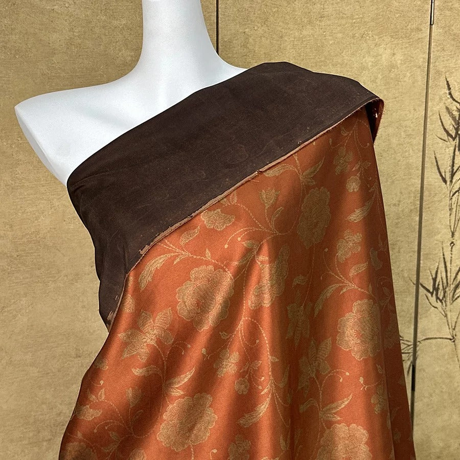 A mannequin wearing a brown and orange floral print dress with a brown shawl draped over it.