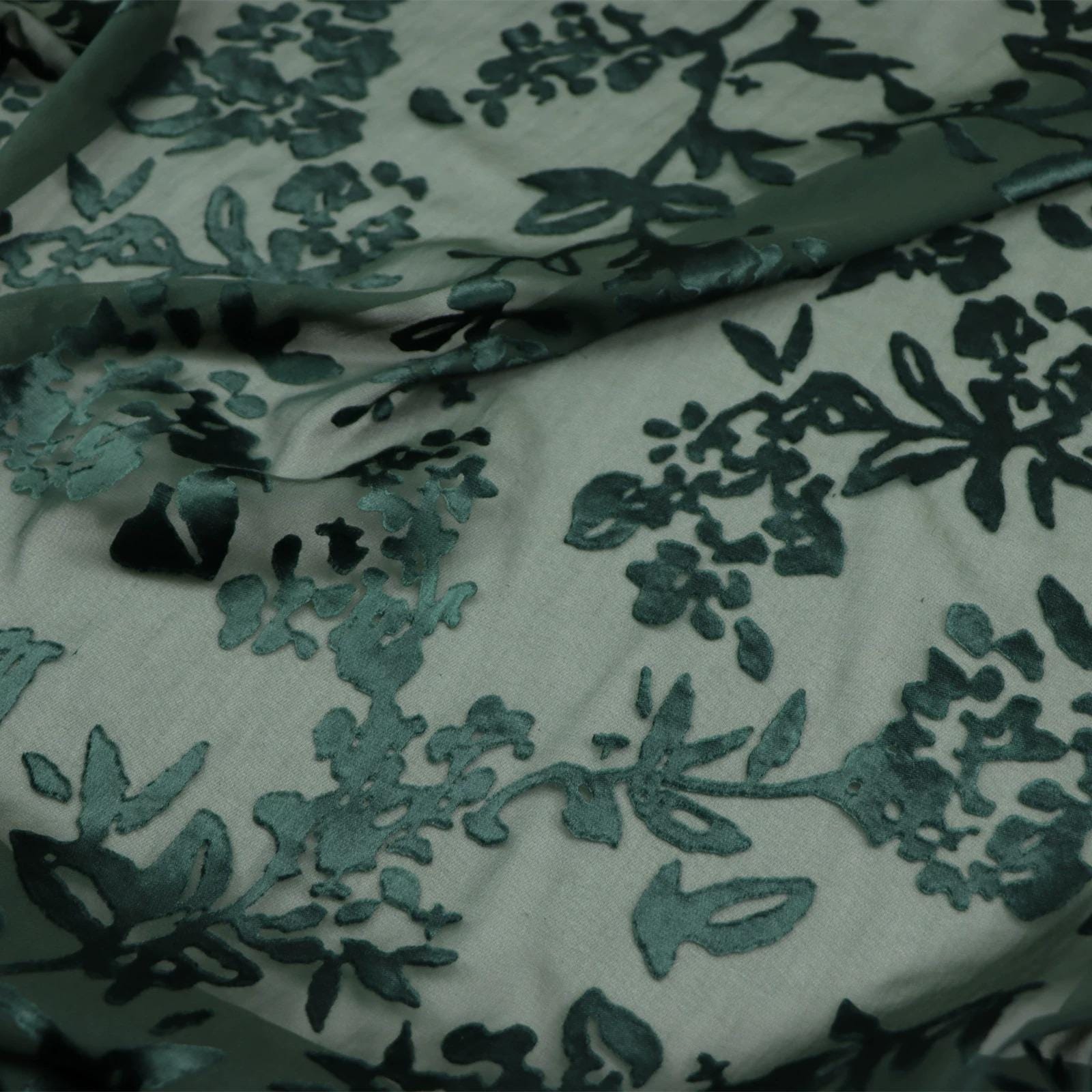 a close-up view of a fabric with a floral pattern, featuring a mix of green and black colors.