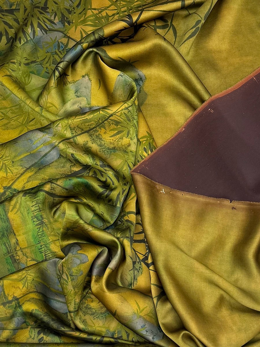 The image is a close-up of a fabric with a vibrant, colorful pattern, featuring a mix of green, yellow, and brown hues. The fabric appears to be made of silk or a similar material, with a crinkled texture that adds depth and visual interest to the composition.