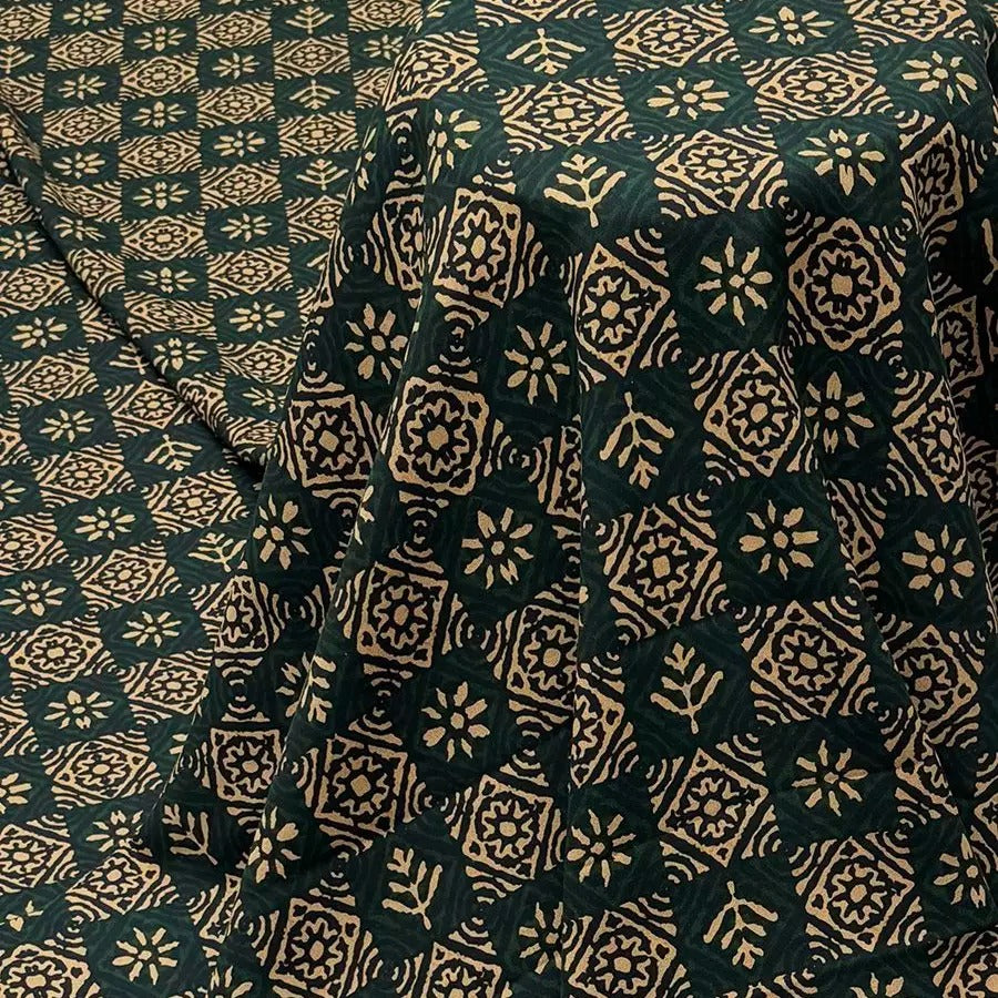 a close-up view of a fabric with a repeating pattern of green and gold geometric shapes, resembling a traditional Indian textile design.