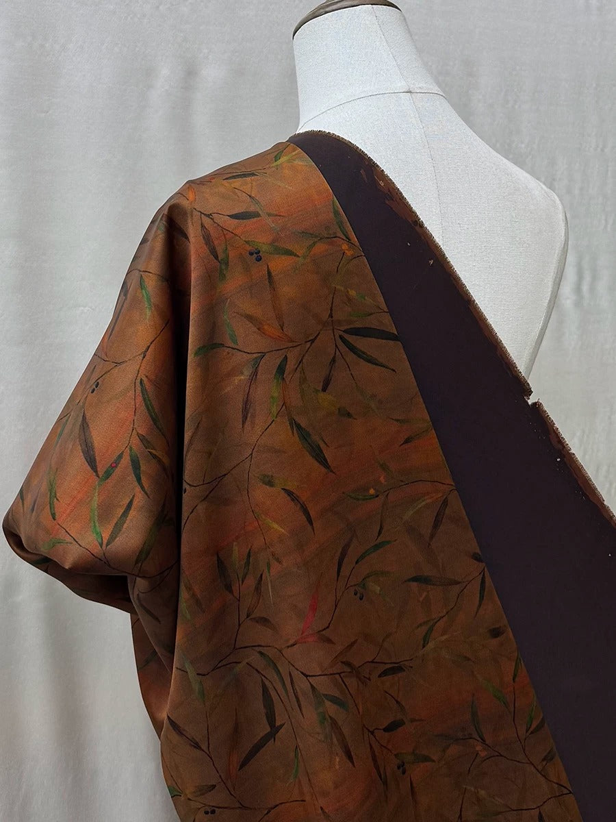 a mannequin wearing a brown and black patterned fabric draped over its shoulder.