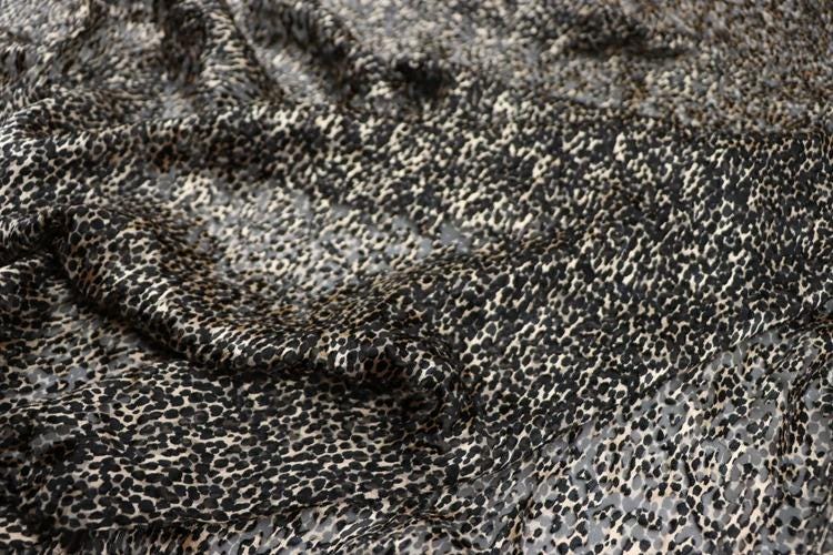 a close-up view of a fabric with a leopard print pattern, featuring a mix of black and white spots.